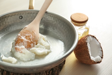 Frying pan with coconut oil on table, closeup