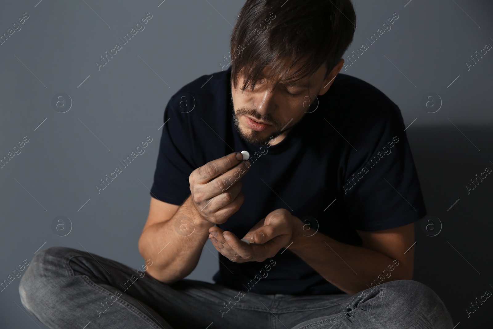 Photo of Young addicted man with drugs on grey background