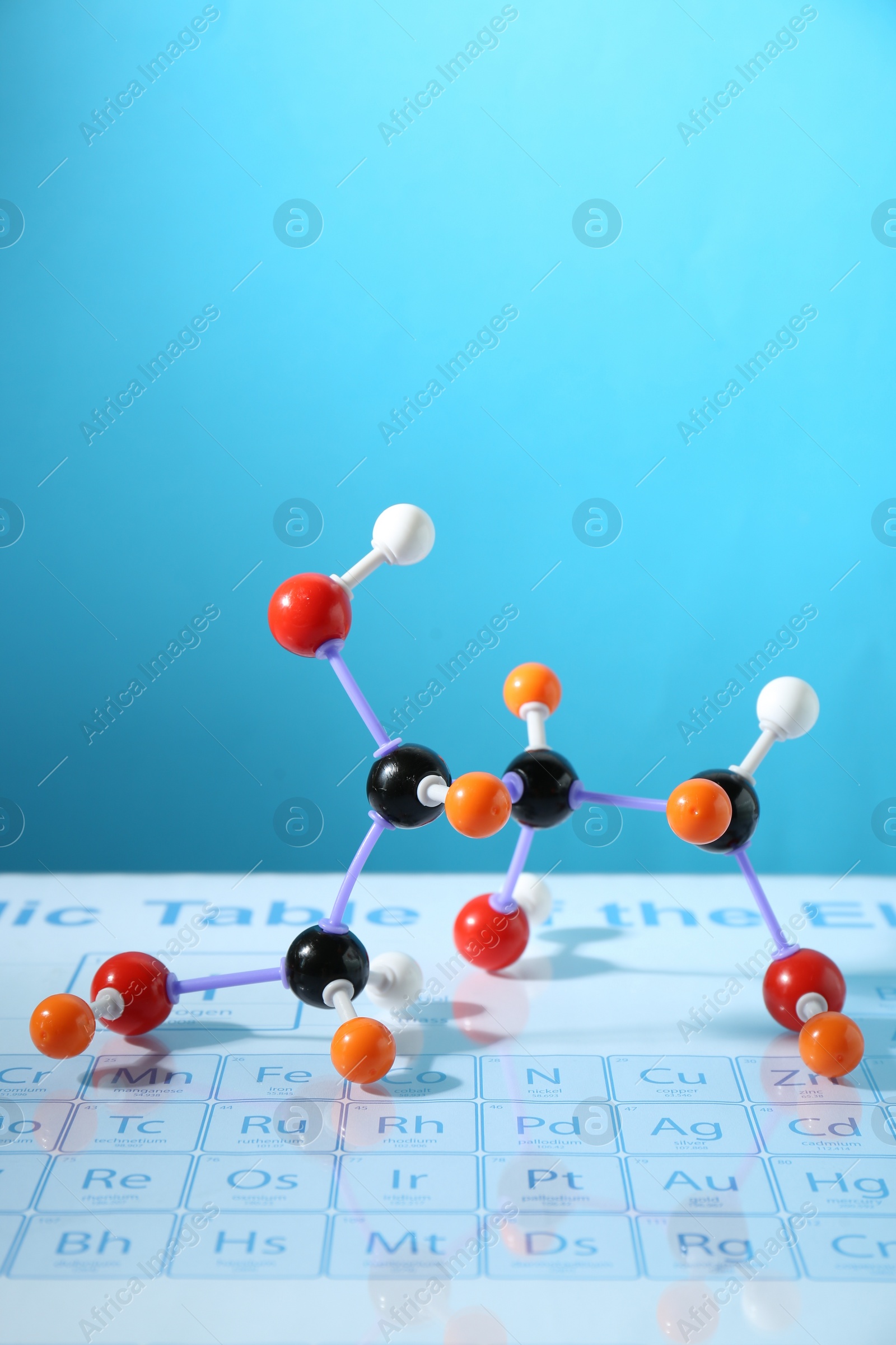 Photo of Molecular model on periodic table against light blue background