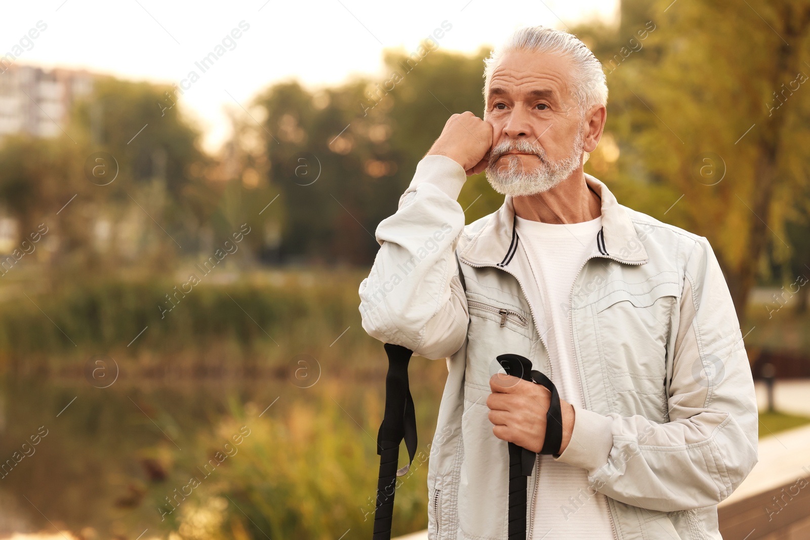 Photo of Senior man with Nordic walking poles outdoors, space for text