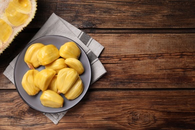 Photo of Delicious exotic jackfruit bulbs on wooden table, flat lay. Space for text