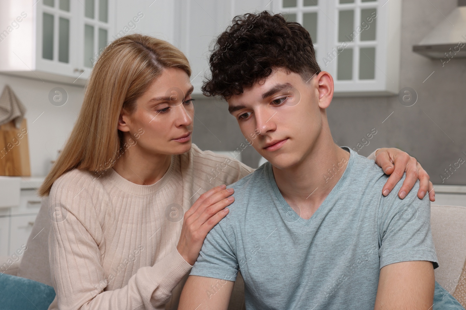 Photo of Mother consoling her upset son at home. Teenager problems