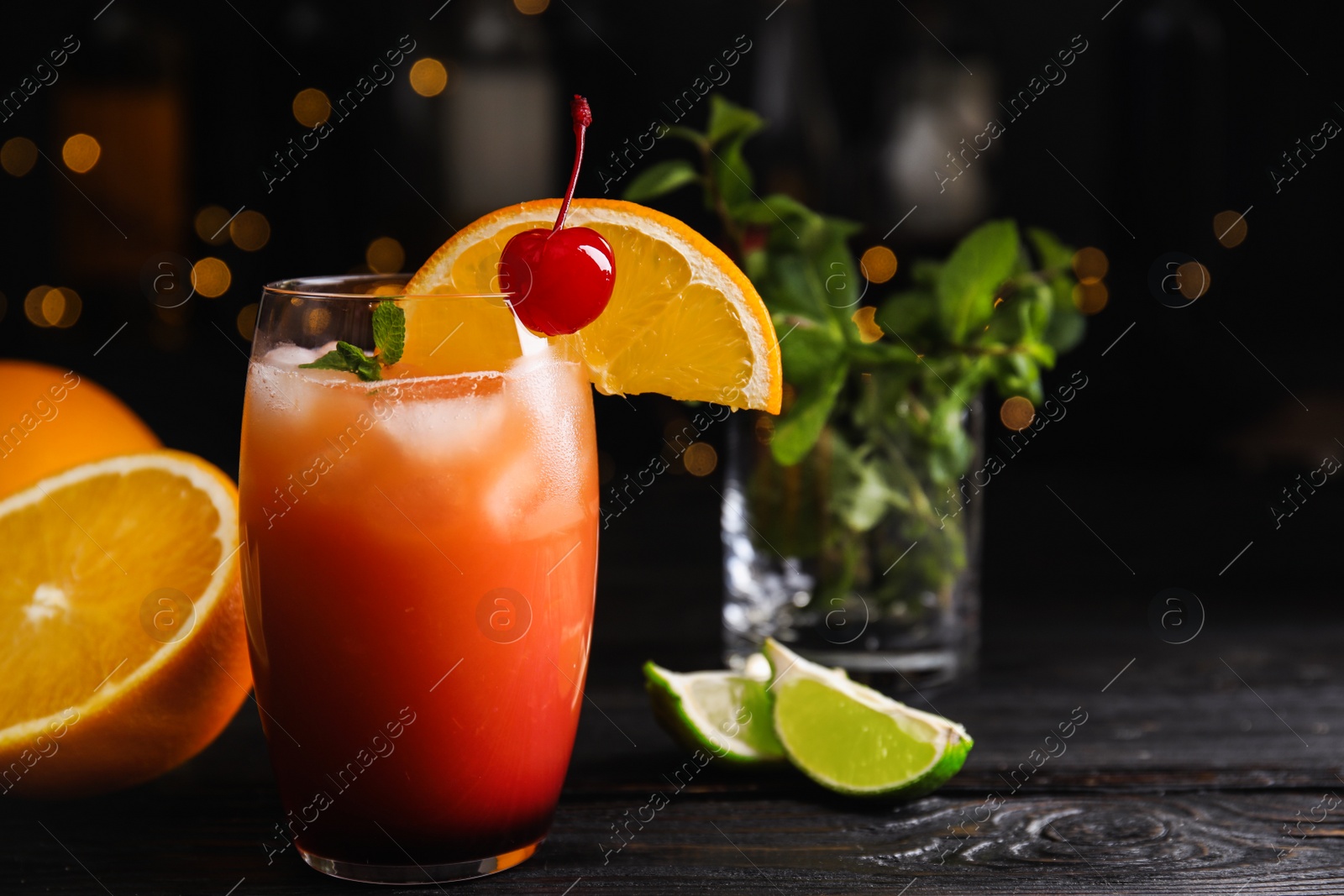 Photo of Fresh alcoholic Tequila Sunrise cocktail on black wooden table