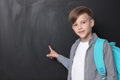 Photo of Cute schoolboy near chalkboard, space for text
