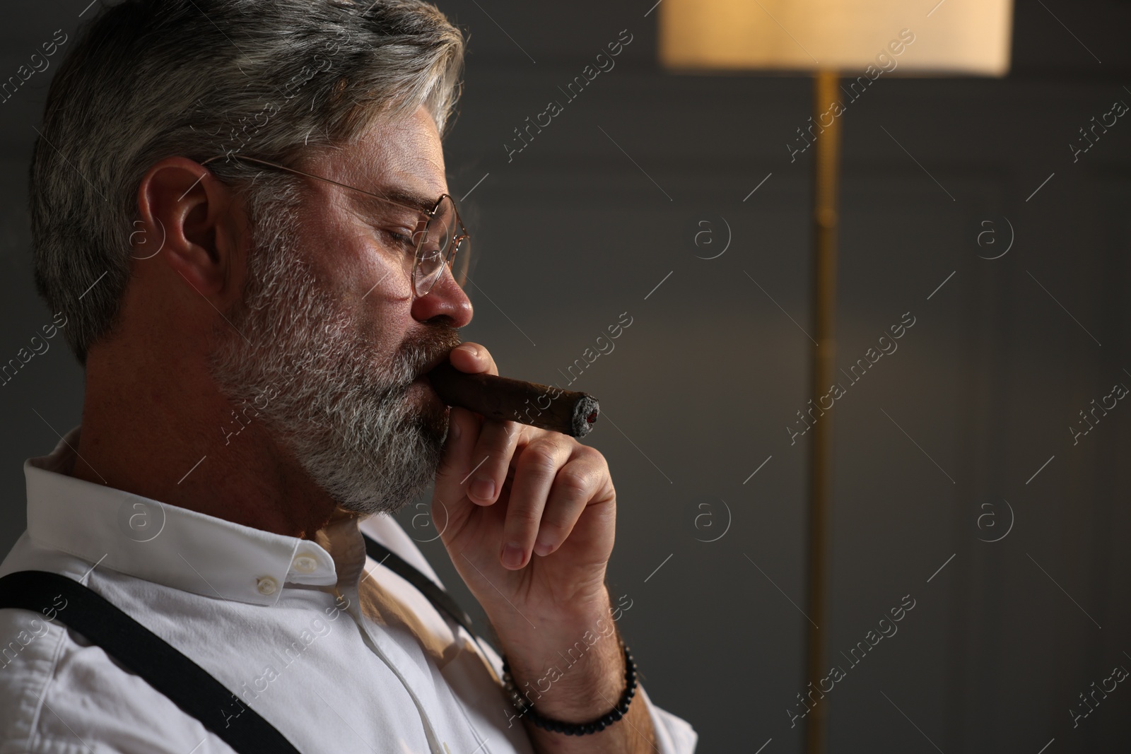 Photo of Bearded man smoking cigar indoors. Space for text