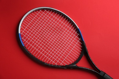 Tennis racket on red background, top view. Sports equipment