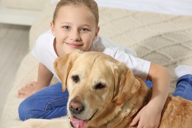 Photo of Cute child with her Labrador Retriever on bed. Adorable pet