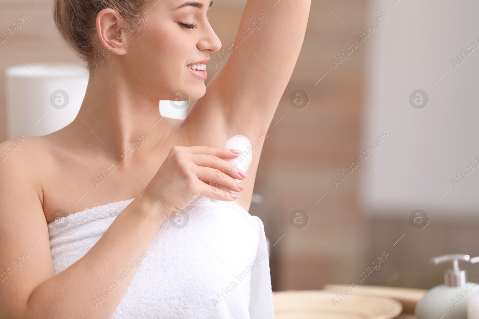 Photo of Beautiful young woman applying deodorant after shower in bathroom. Space for text