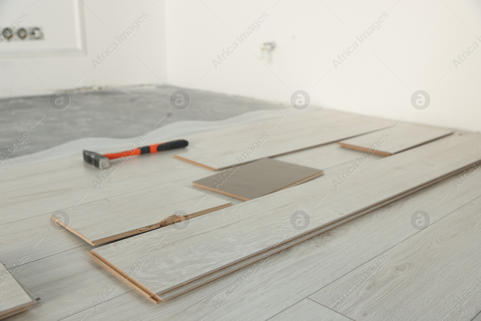 Photo of Parquet planks and hammer on floor in room prepared for renovation
