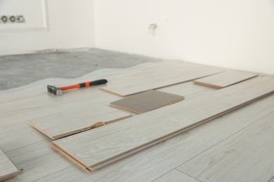 Photo of Parquet planks and hammer on floor in room prepared for renovation