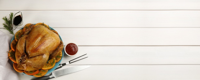 Photo of Delicious chicken with oranges and rosemary on white wooden table, flat lay. Space for text