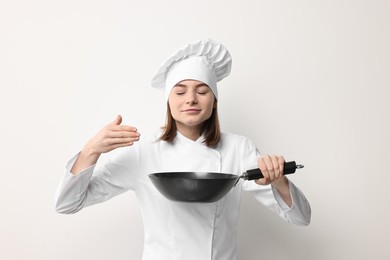 Professional chef with frying pan on light background