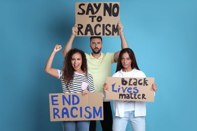 Photo of Protesters demonstrating different anti racism slogans on light blue background. People holding signs with phrases