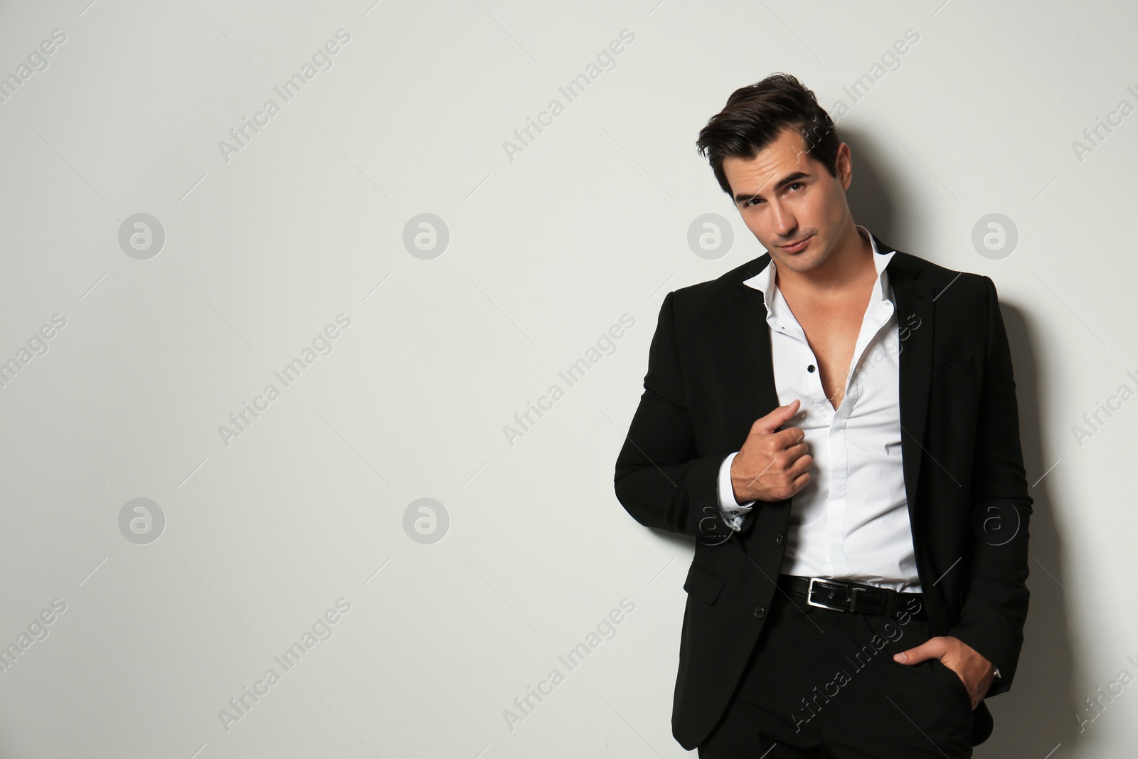 Photo of Handsome young man in elegant suit on light beige background. Space for text