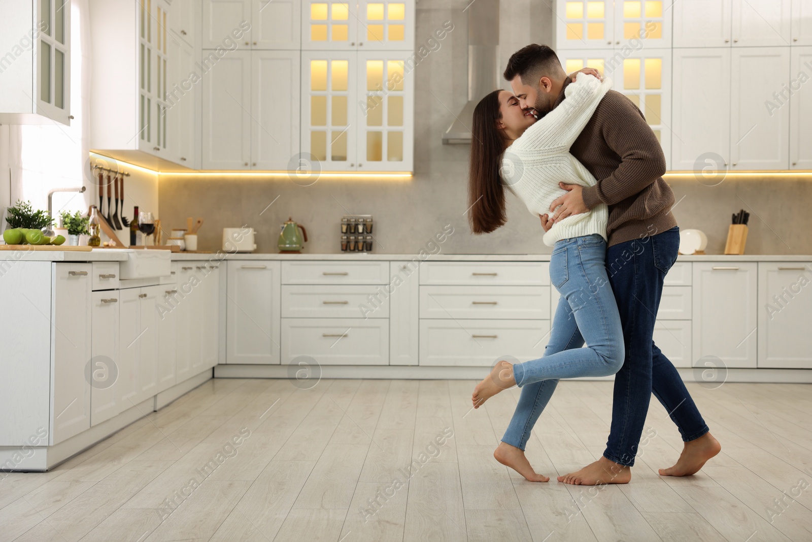 Photo of Affectionate young couple kissing in kitchen. Space for text