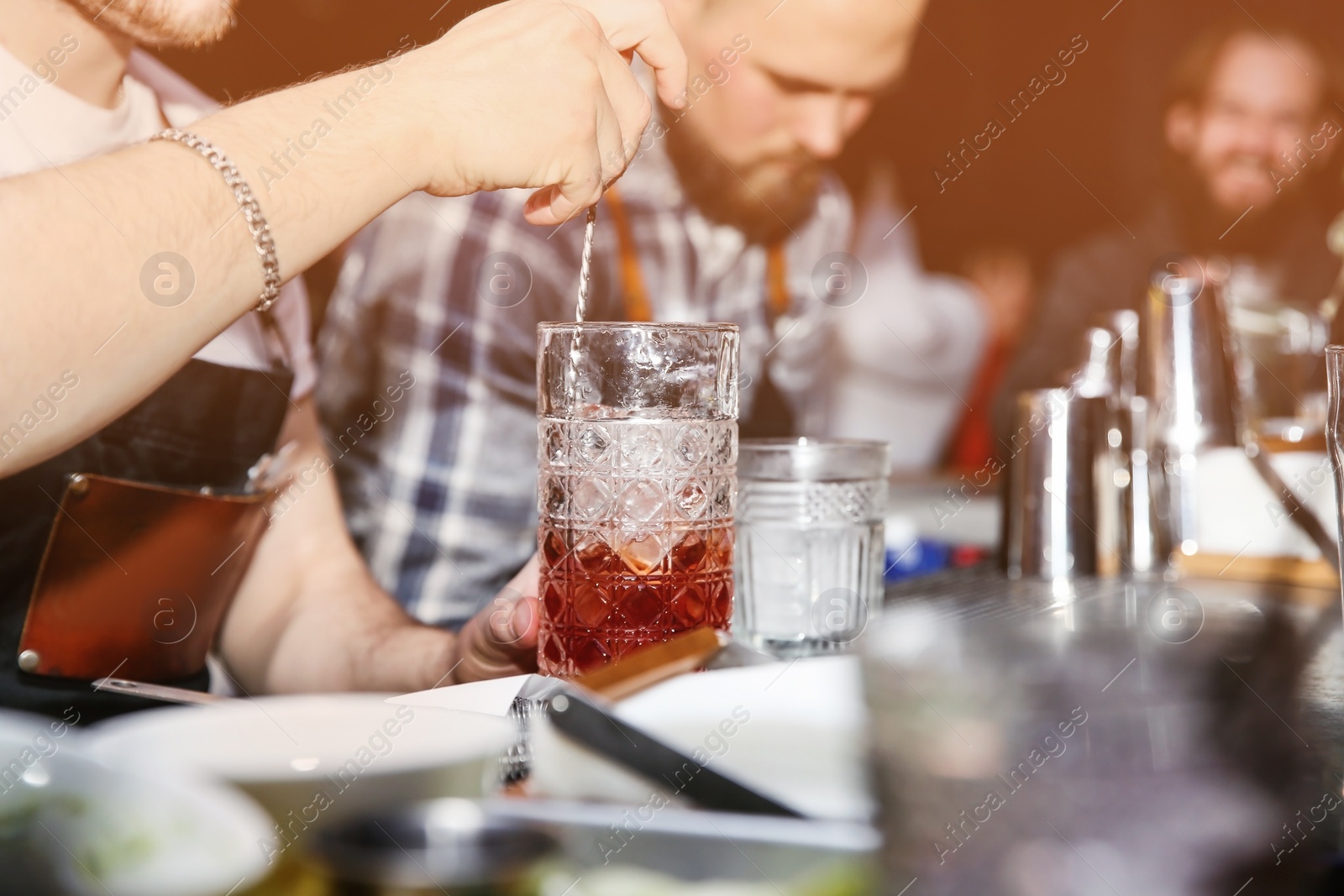 Photo of Bartender preparing tasty cocktail at counter in nightclub, closeup