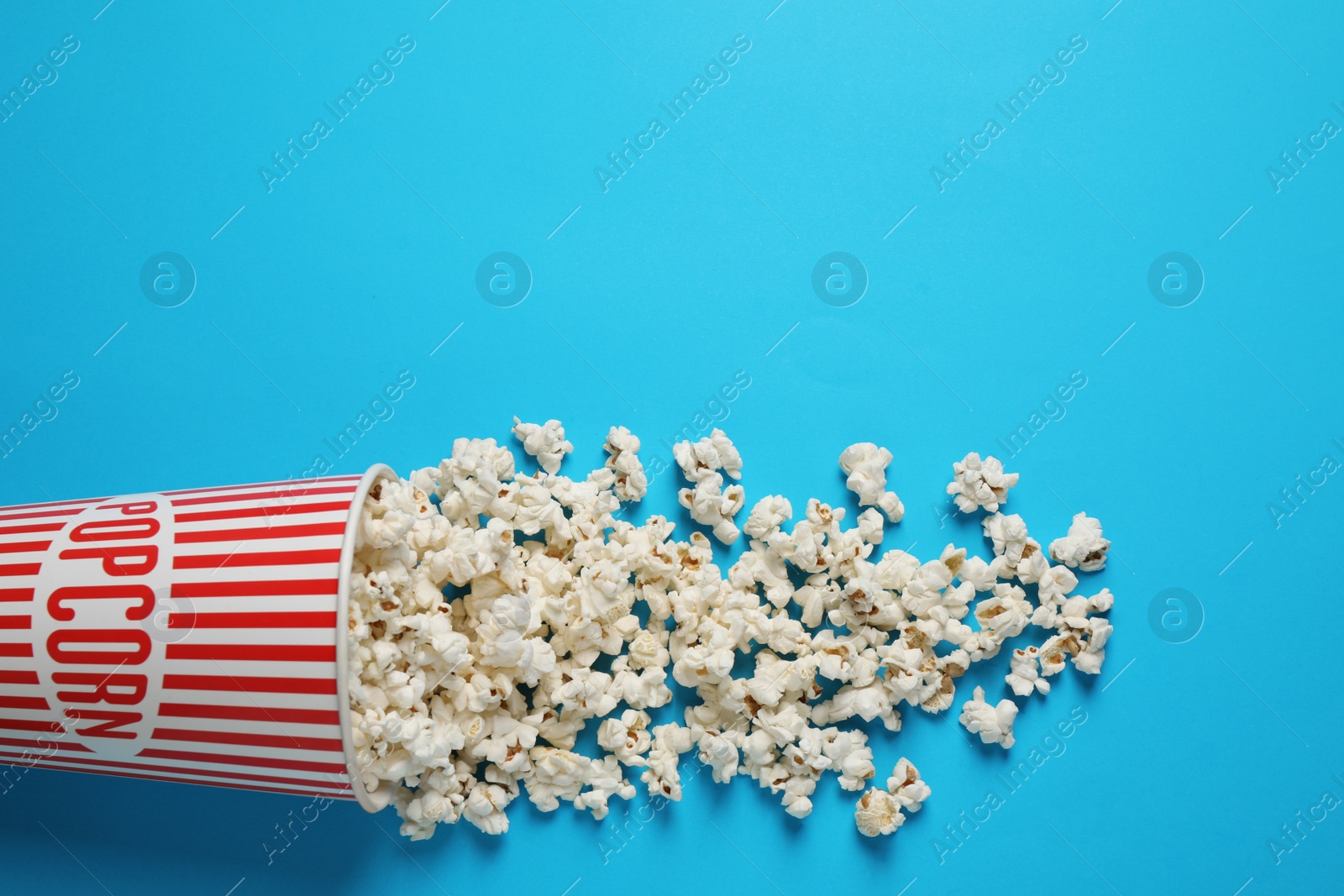 Photo of Delicious popcorn on light blue background, top view. Space for text