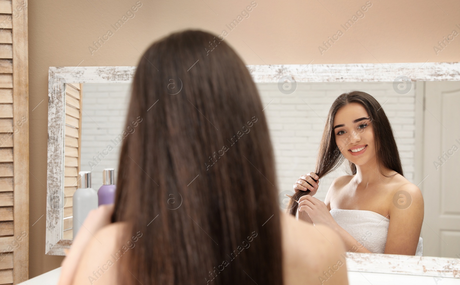 Photo of Beautiful young woman with hair comb near mirror in bathroom