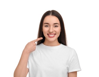 Young woman pointing at her clean teeth and smiling on white background
