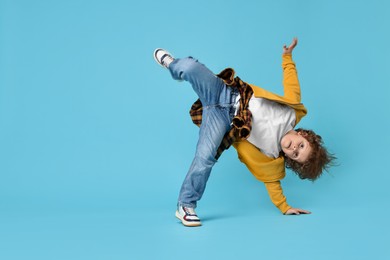 Photo of Happy little boy dancing on light blue background