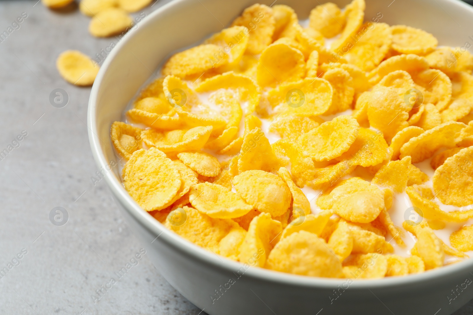 Photo of Tasty corn flakes with milk on light grey table, closeup