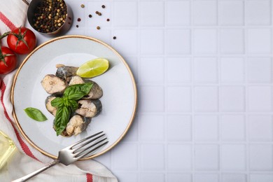 Photo of Canned mackerel chunks served on white tiled table, flat lay. Space for text
