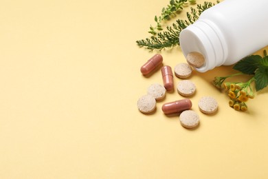 Photo of Different pills and herbs on light yellow background, space for text. Dietary supplements