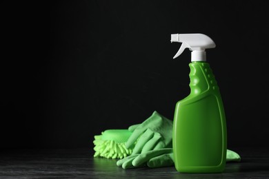 Photo of Spray bottle, rubber gloves and microfiber sponge on black table, space for text. Car products