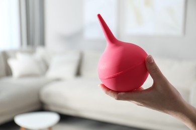 Photo of Woman holding pink enema at home, closeup. Space for text