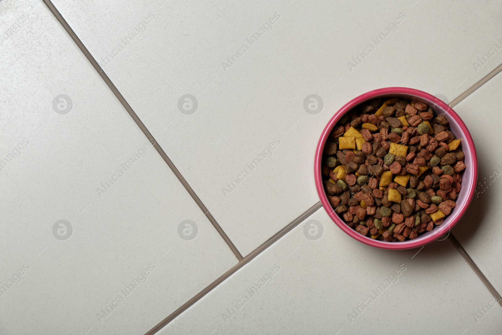 Photo of Pet bowl with dry food on floor, top view. Space for text