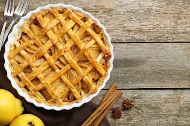 Photo of Tasty homemade quince pie served on wooden table, flat lay. Space for text