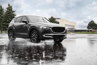 Modern car driving outdoors on rainy day