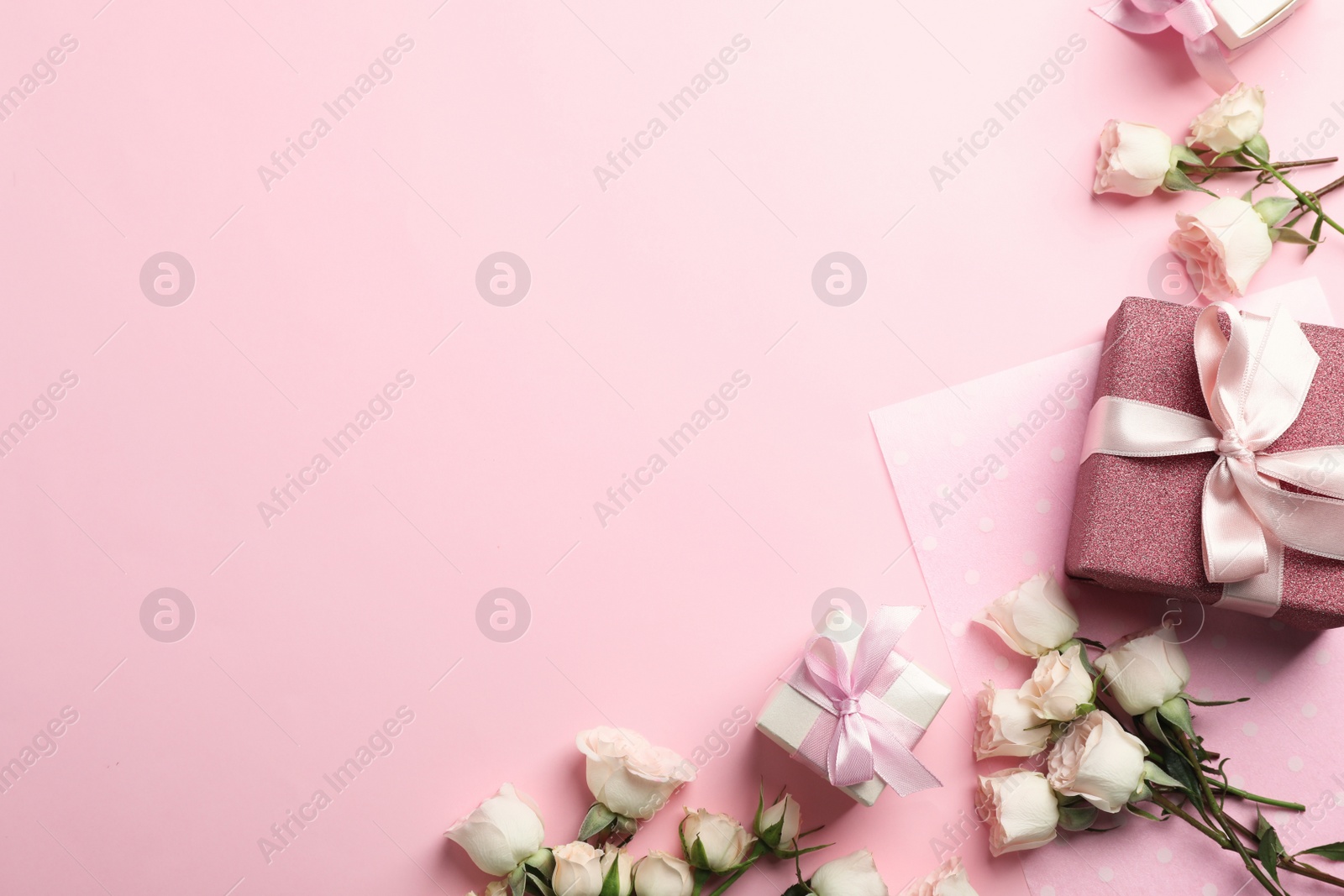 Photo of Flat lay composition with beautiful roses and gift boxes on color background. Space for text