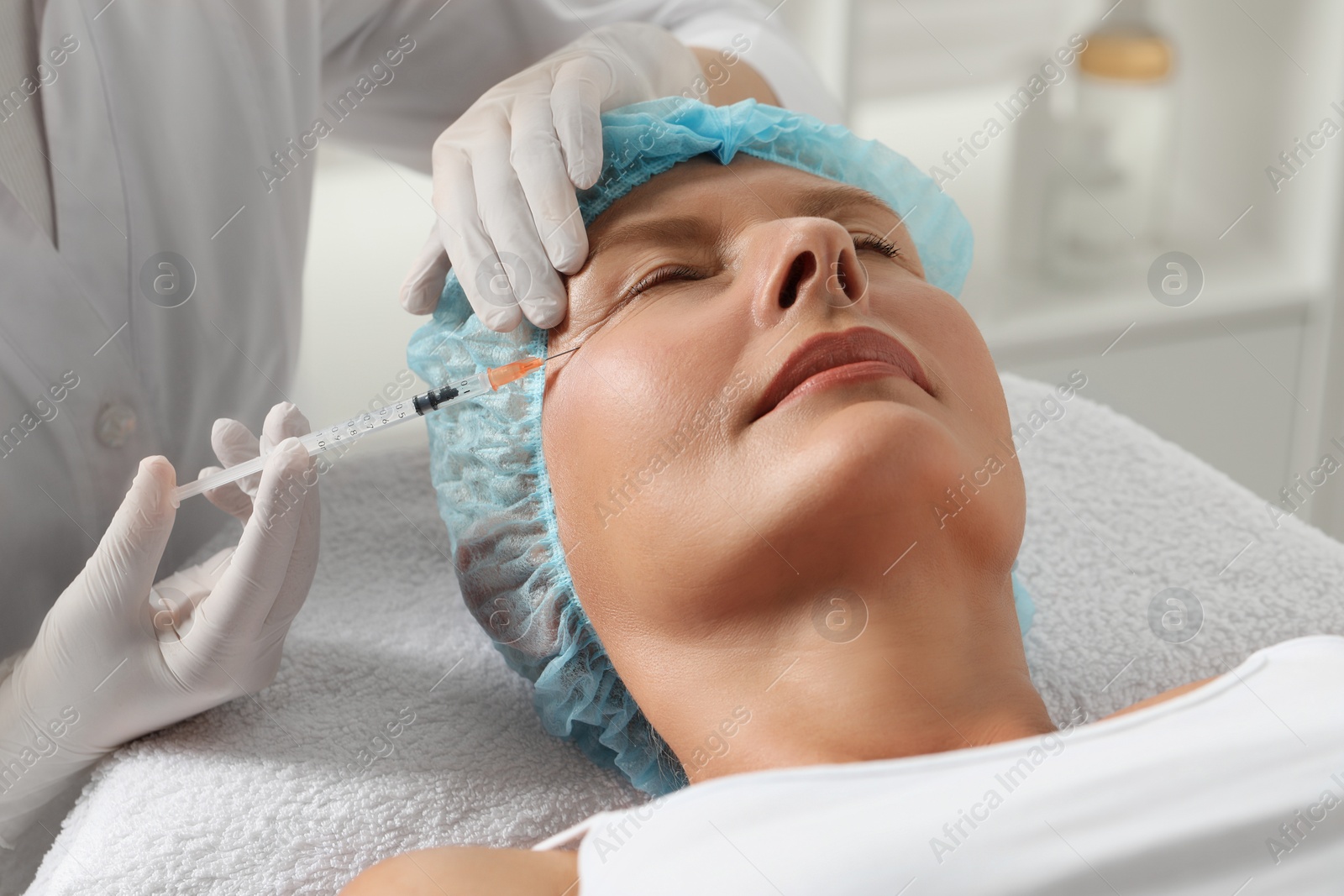 Photo of Doctor giving facial injection to senior woman in clinic, closeup. Cosmetic surgery