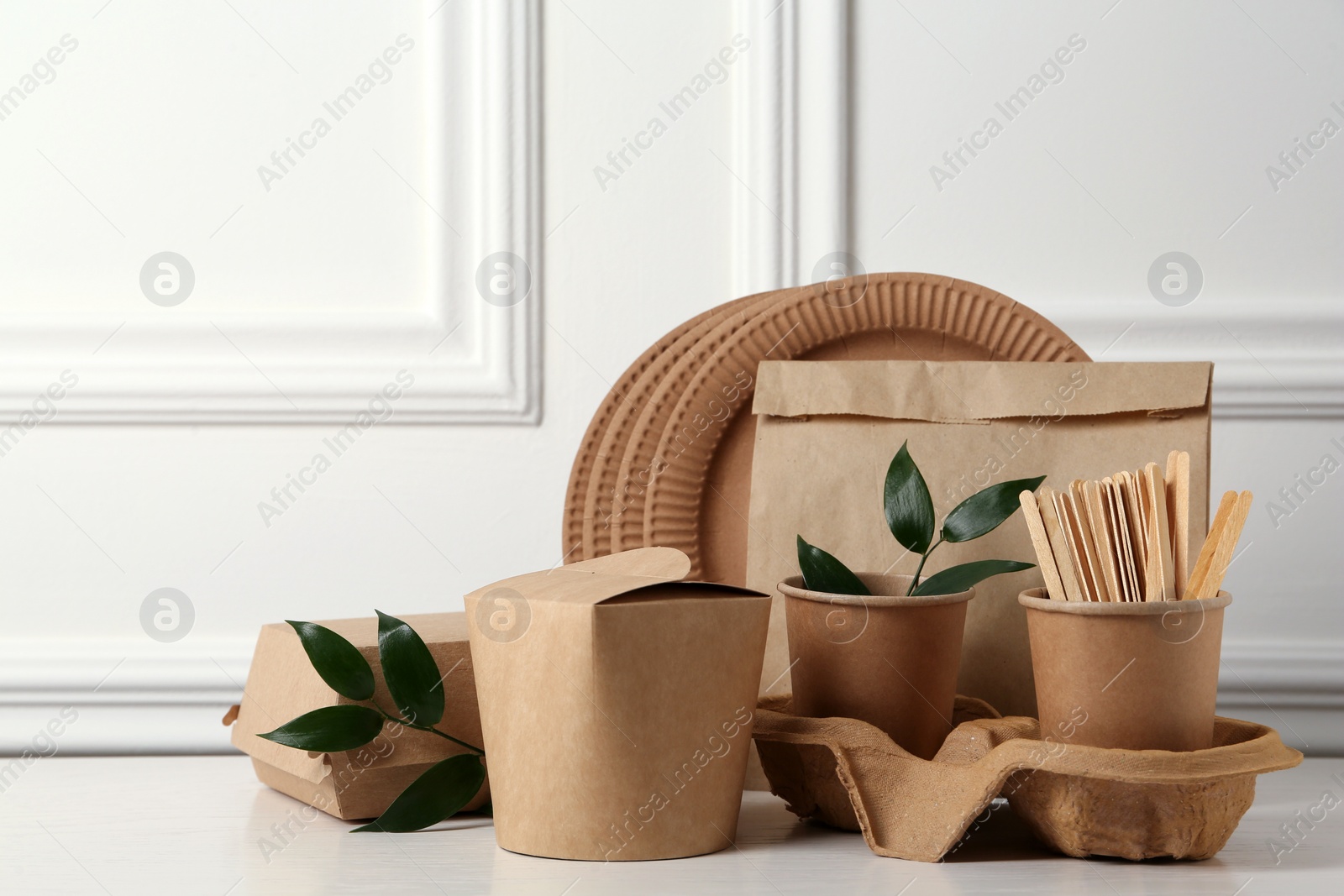 Photo of Disposable eco friendly products on white wooden table