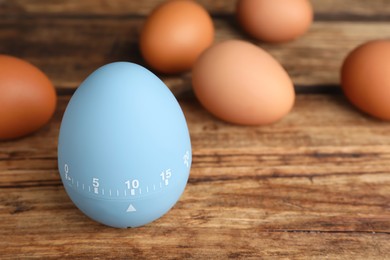 Kitchen timer and eggs on wooden table. Space for text
