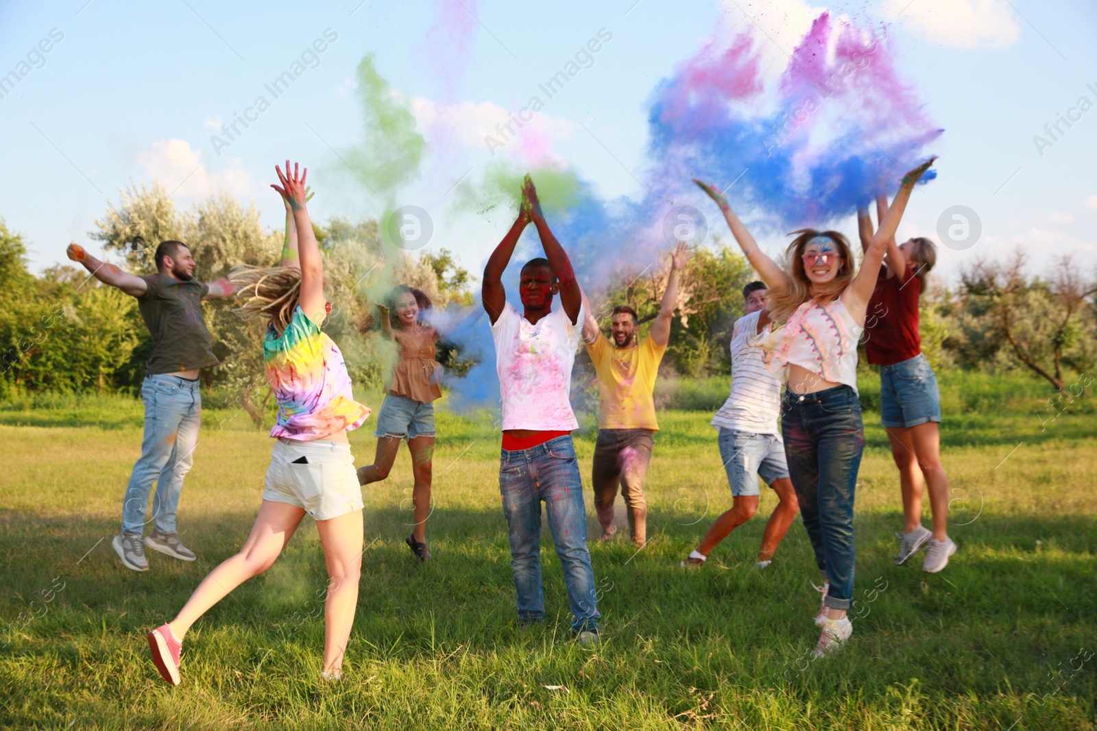 Photo of Happy friends having fun with colorful powder dyes outdoors. Holi festival celebration