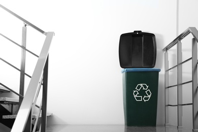 Trash bin on stair landing indoors. Waste recycling