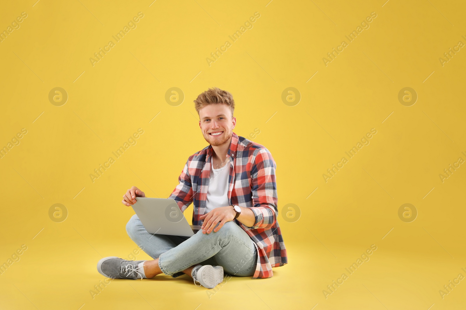 Photo of Happy man with laptop on yellow background