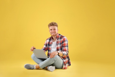 Photo of Happy man with laptop on yellow background