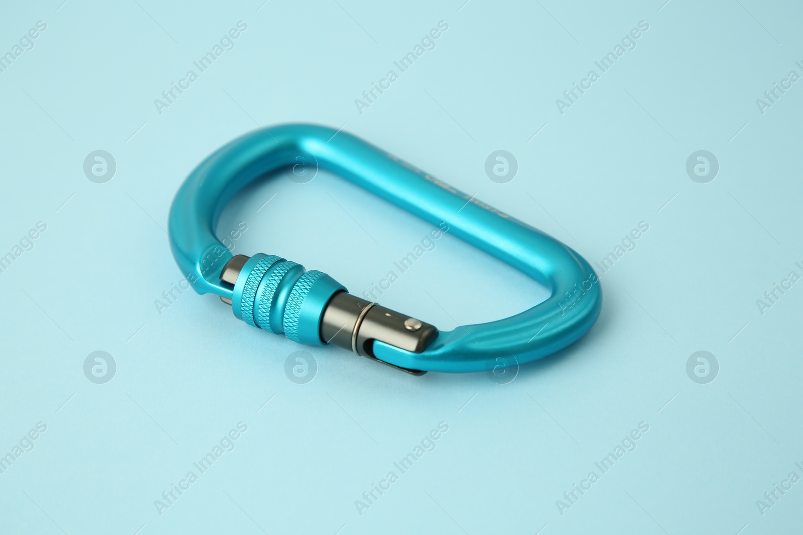 Photo of One carabiner on light blue background, closeup