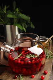 Photo of Tasty hot cranberry tea and fresh ingredients on wooden table