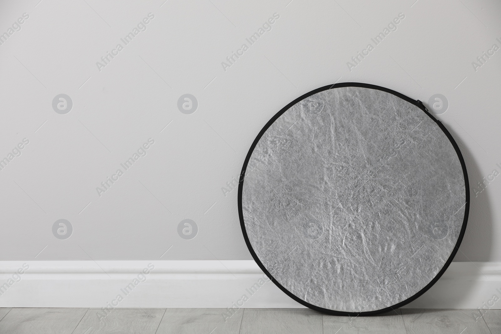 Photo of Studio reflector near grey wall in room, space for text. Professional photographer's equipment