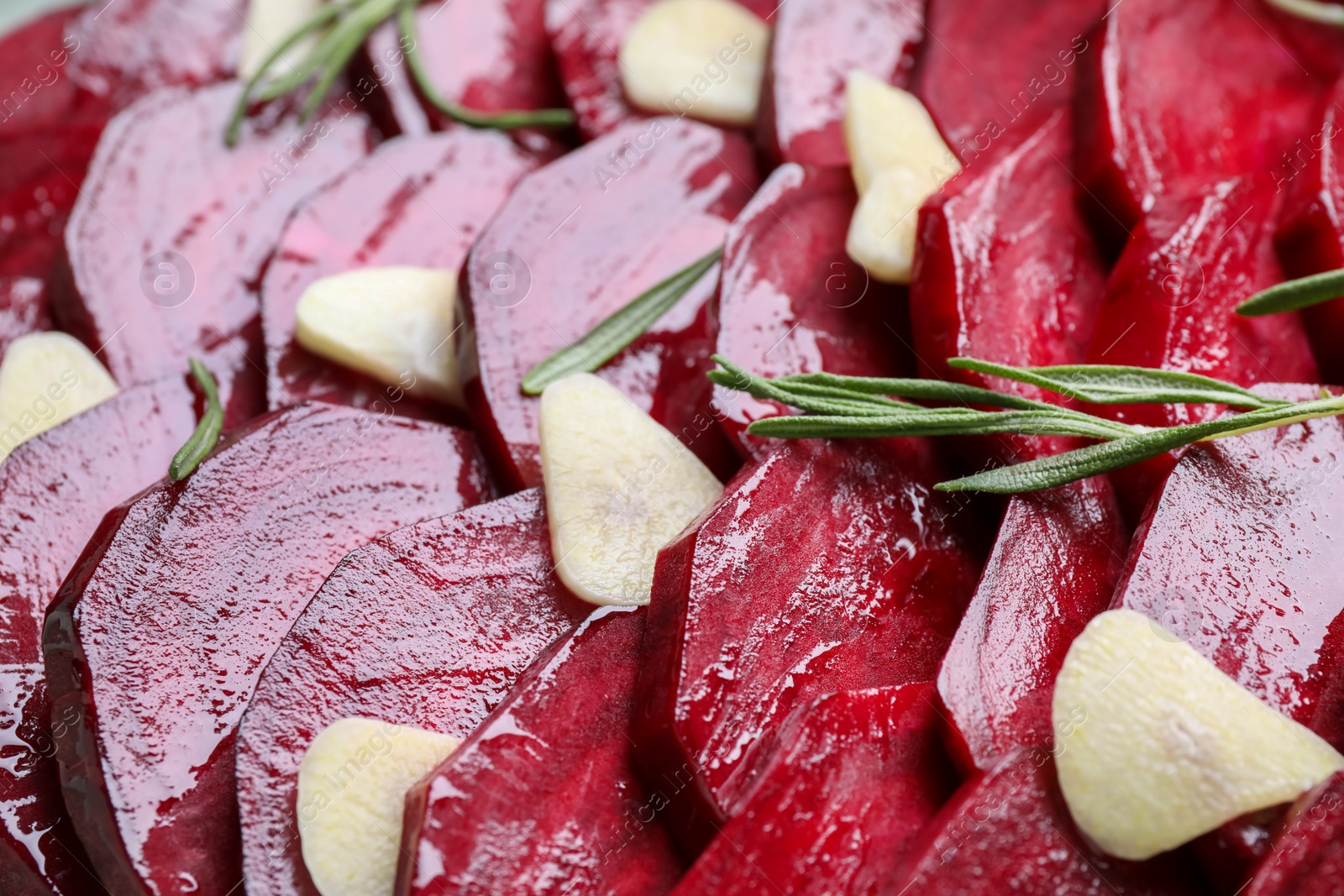 Photo of Raw beetroot slices, garlic and rosemary as background, closeup