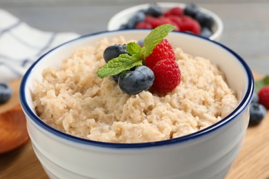 Photo of Tasty oatmeal porridge with berries in bowl, closeup