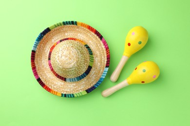 Mexican sombrero hat and maracas on green background, flat lay