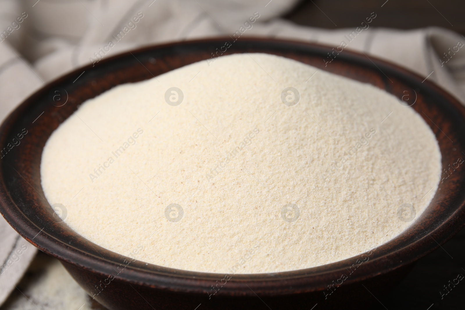 Photo of Uncooked organic semolina in bowl on table, closeup