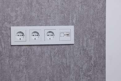Photo of Electric power sockets on grey wall indoors, space for text