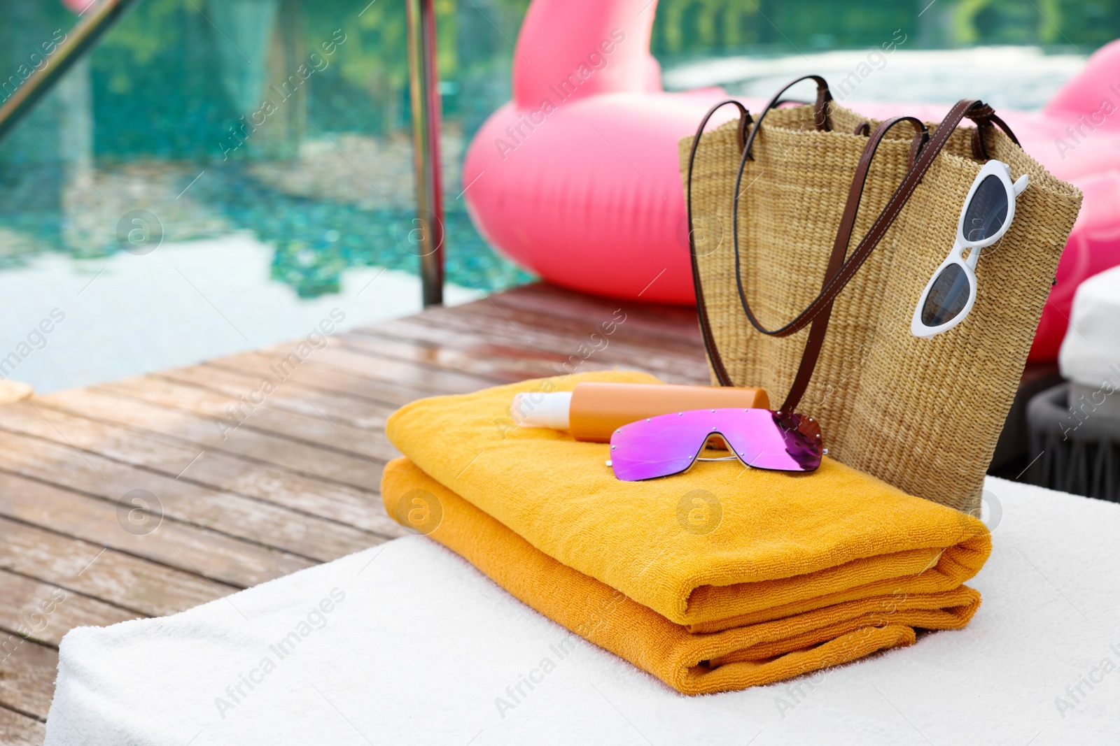 Photo of Wicker bag with beach accessories on sun lounger near outdoor swimming pool, space for text. Luxury resort