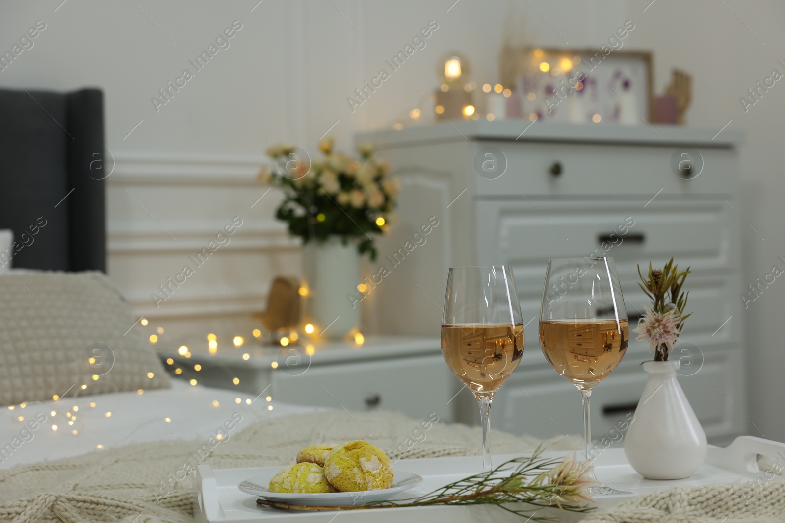 Photo of Tray with glasses of wine and cookies in bedroom adorned for romantic date. Space for text